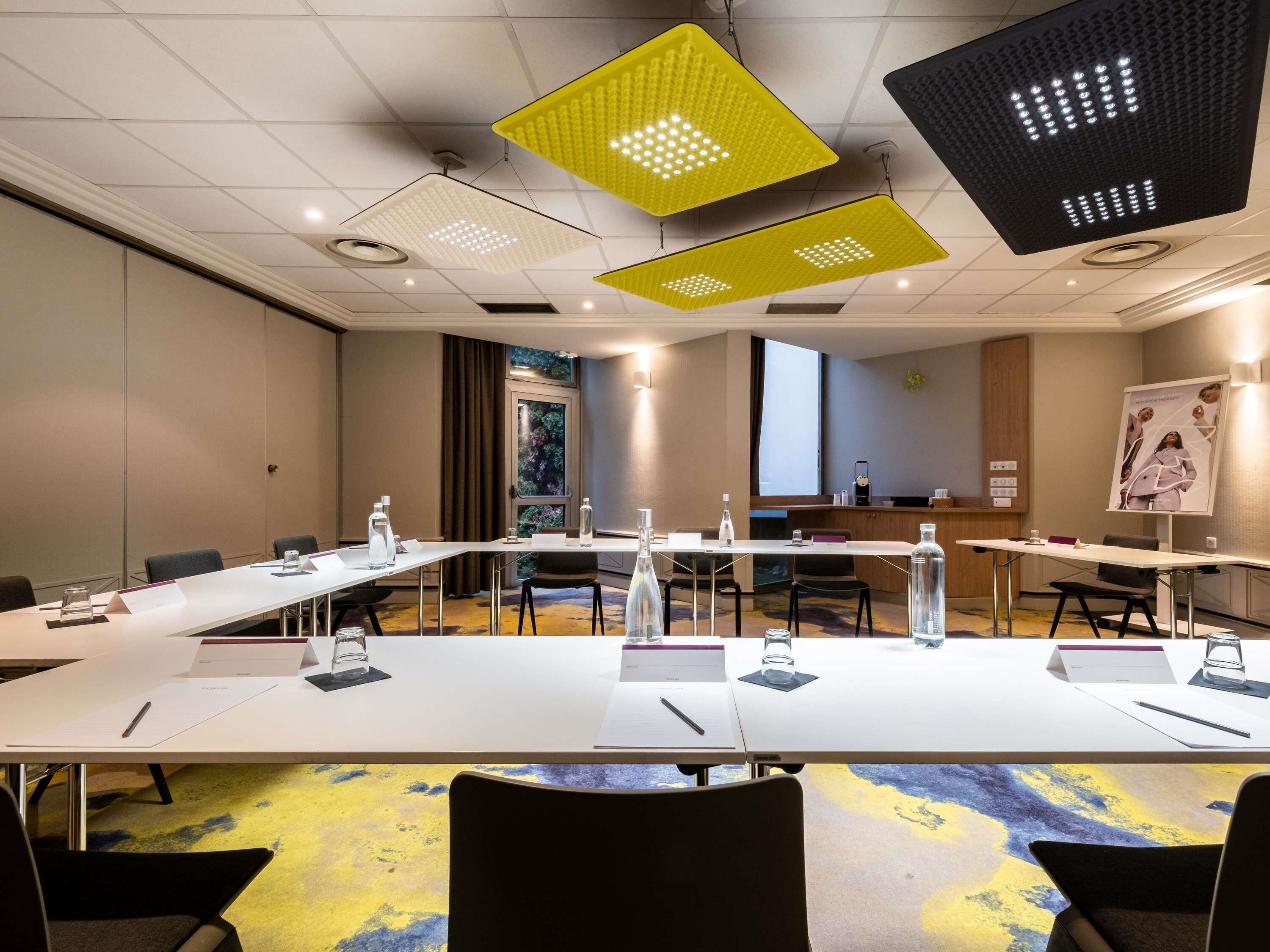 Un salón de conferencias con una larga mesa, sillas e iluminación colgante.