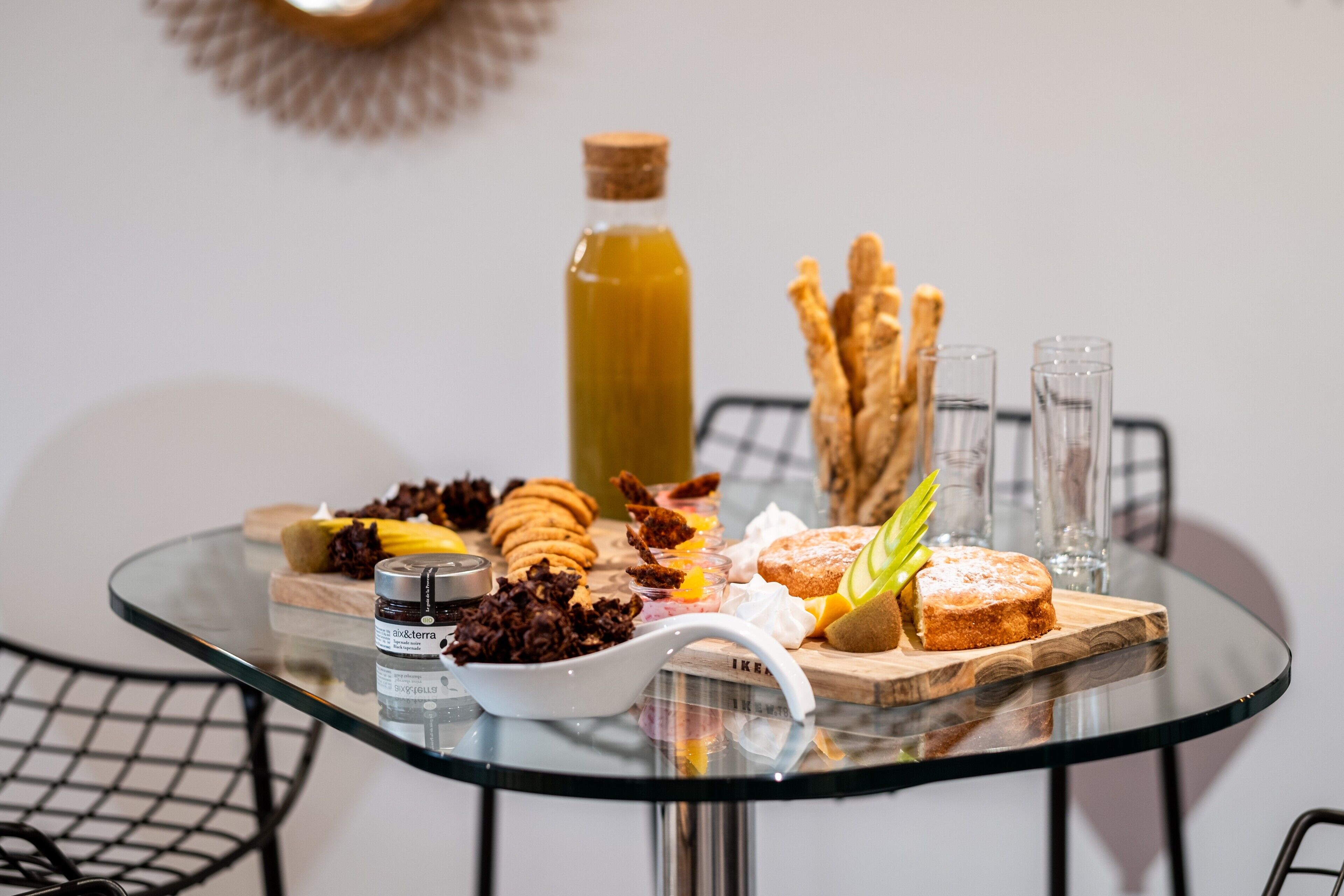 A glass table with a variety of pastries and a bottle of juice.