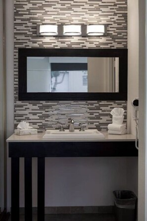 Un bany modern amb un respatller d'azulejos, un mirall gran, un rentapel o blanc i un penjamantes.