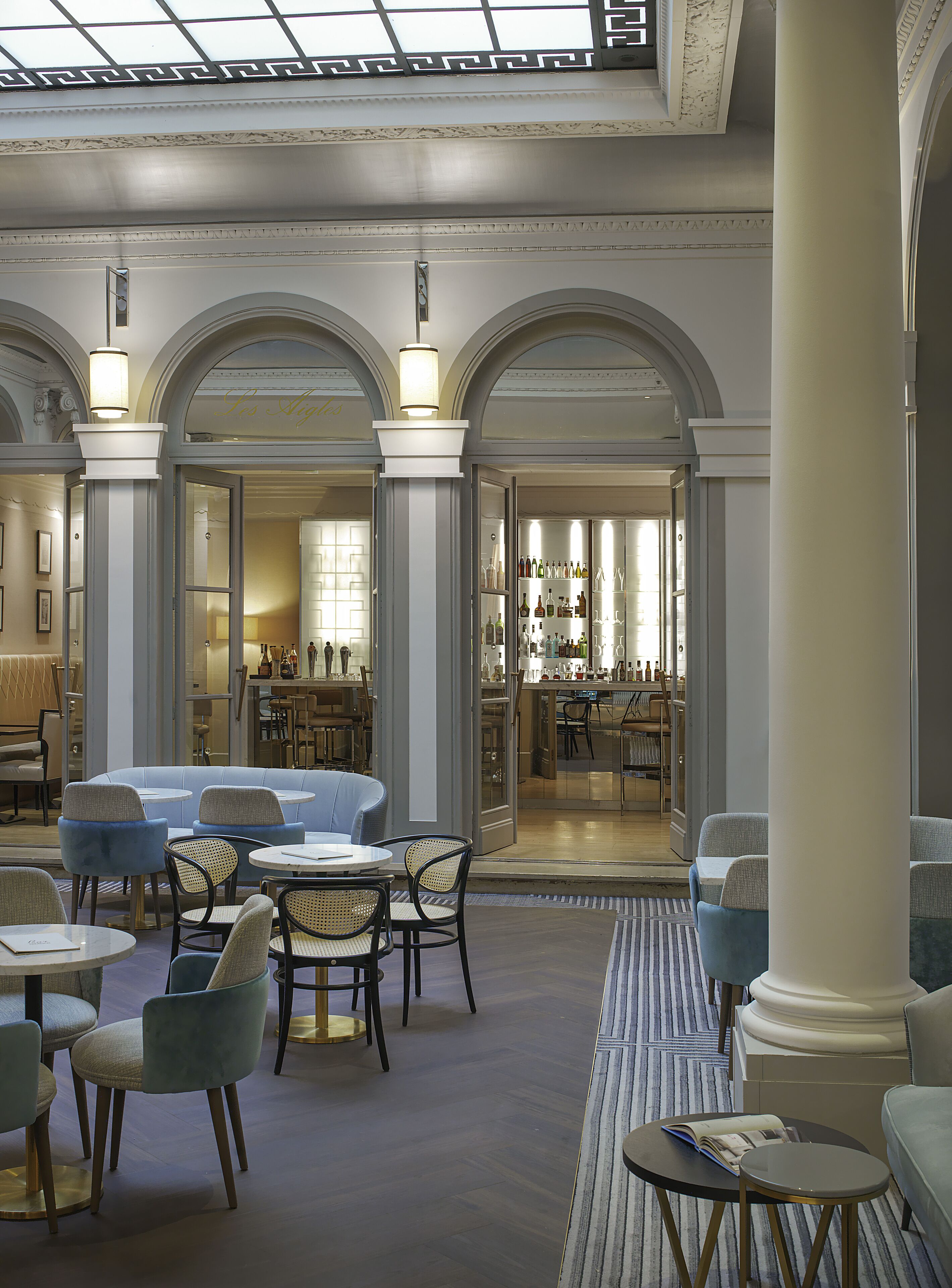 A spacious lobby with seating areas, a bar, and a view of the bar area through an open doorway.