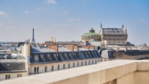 A view of Parisian rooftops with the Eiffel Tower and the Louvre Pyramid in the background. - Paris Marriott Opera Ambassador (Paris)