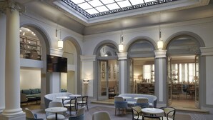 A spacious hotel lobby with multiple seating areas, a bar, and a television. - Paris Marriott Opera Ambassador (Paris)