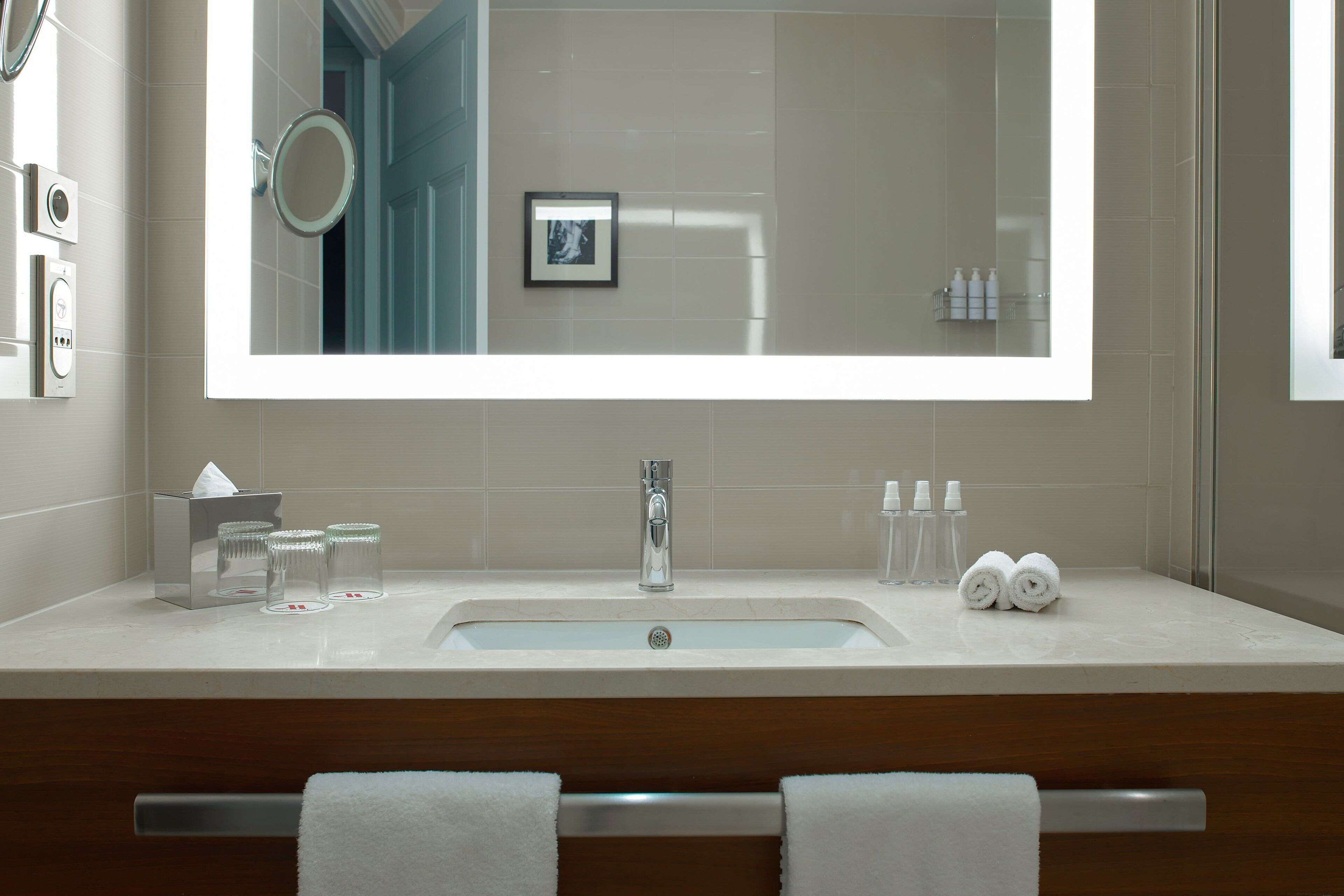 A modern bathroom with a large mirror, a sink, and a towel rack.