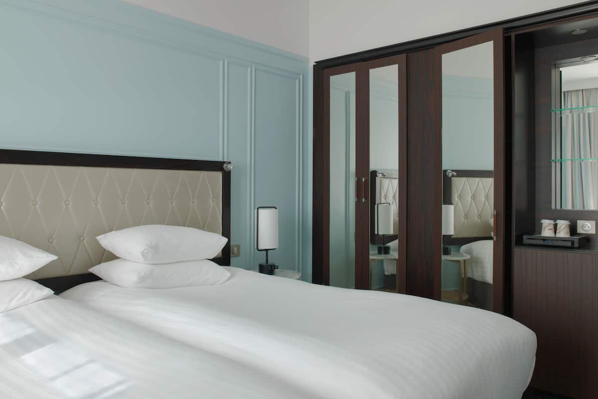 A hotel room with a large bed, a wardrobe, and a mirror.