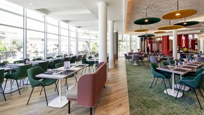 Un restaurante espacioso con techos altos, ventanas amplias y mobiliario moderno.
