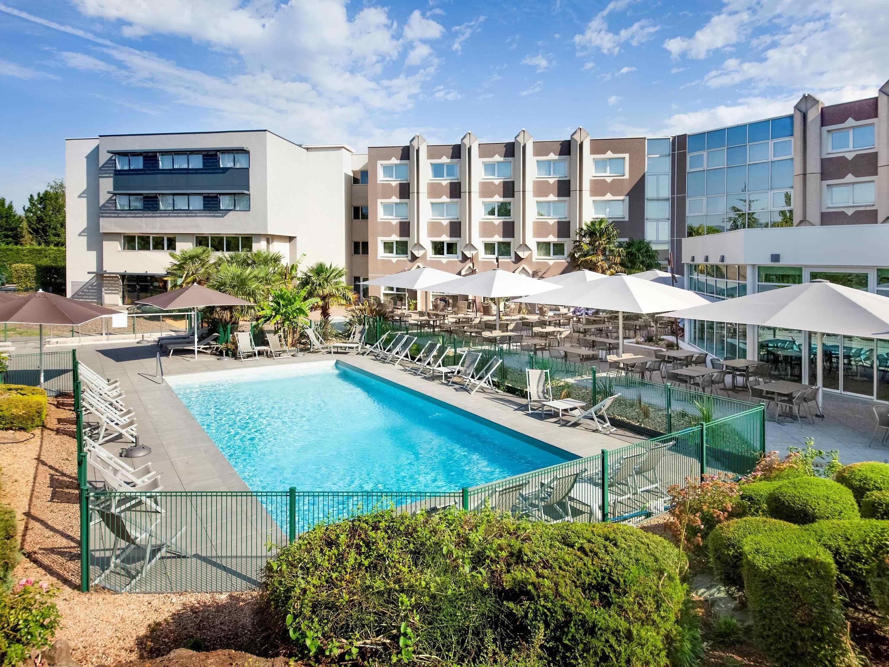 Ein Hotel mit Pool, Außenbereich und einer modernen Gebäudefassade.