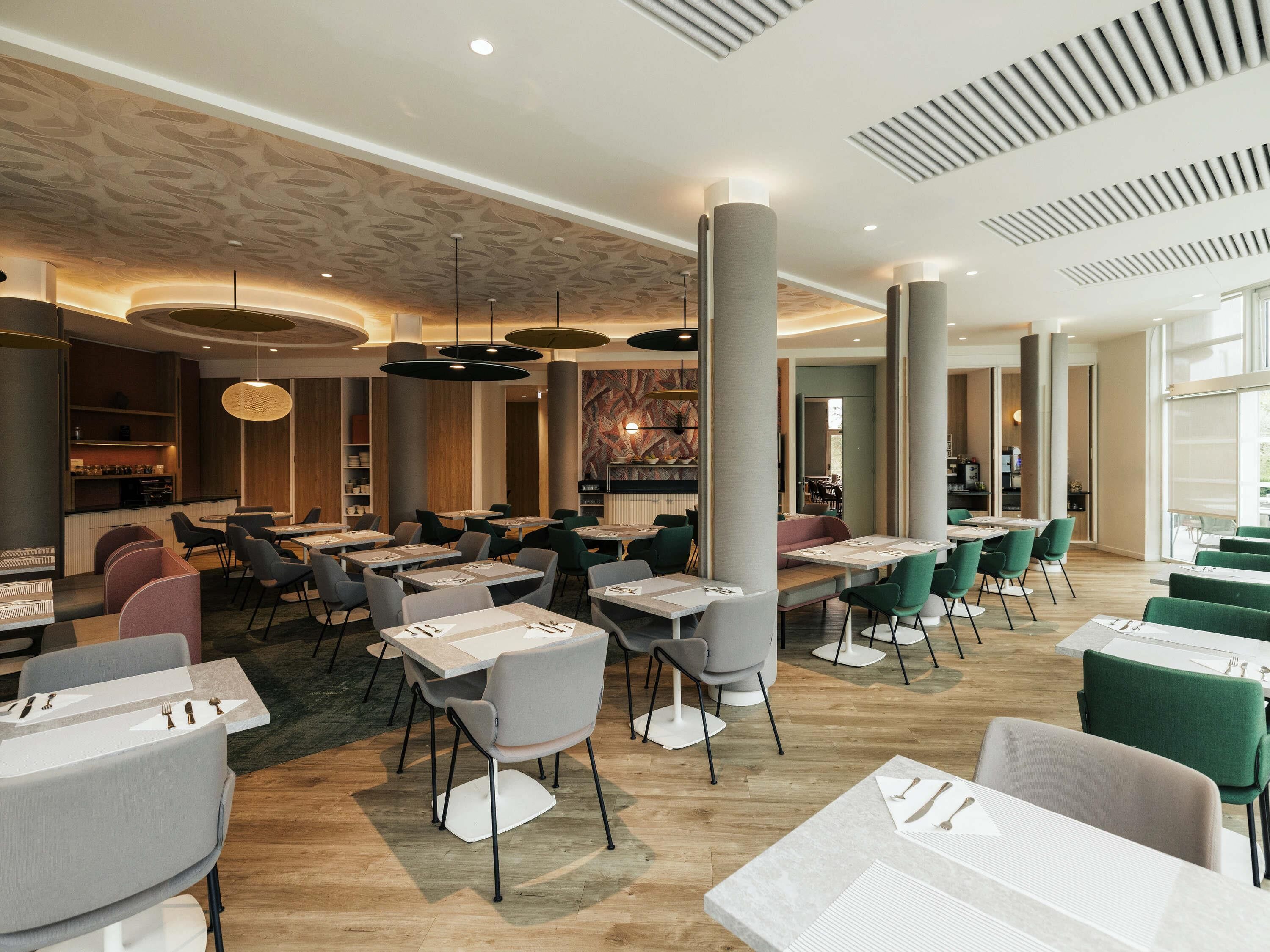 A spacious restaurant with multiple dining areas, high ceilings, and modern lighting fixtures.