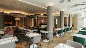 Un restaurant spacieux doté de plusieurs espaces de restauration, de hauts plafonds et d’un éclairage moderne.