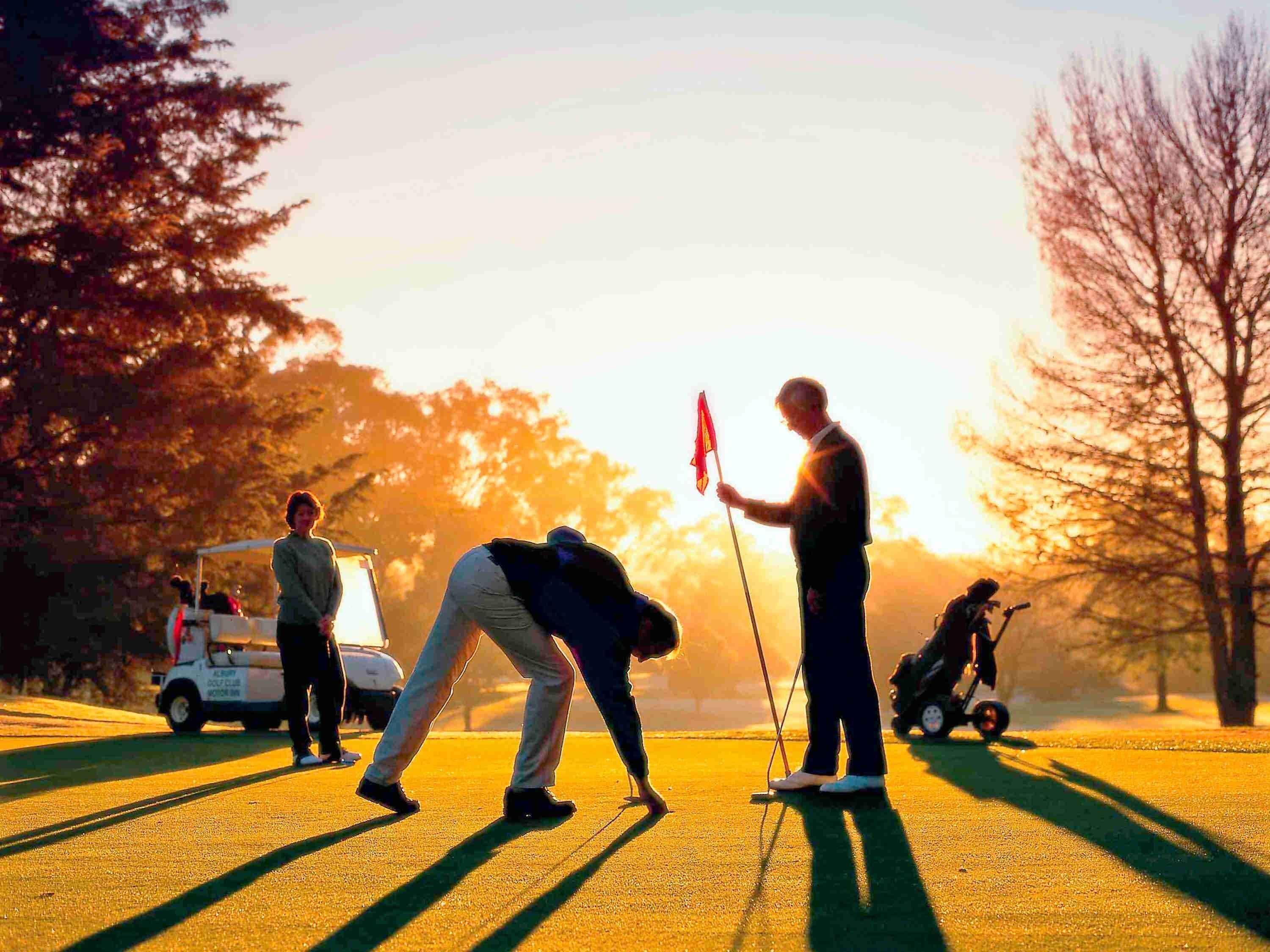 Een golfbaan met spelers en een golfkar.