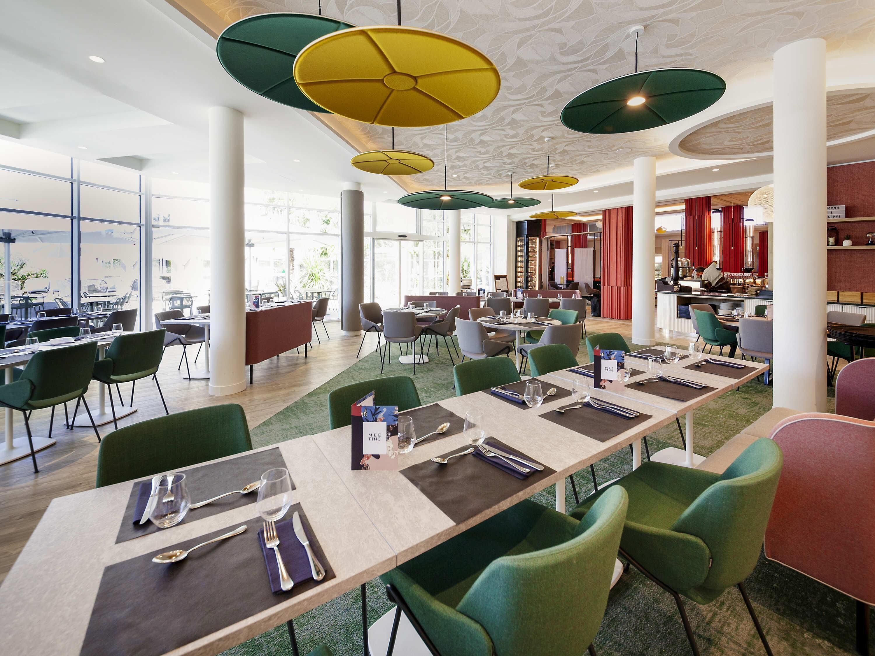A spacious dining area with multiple tables, chairs, and hanging pendant lights.