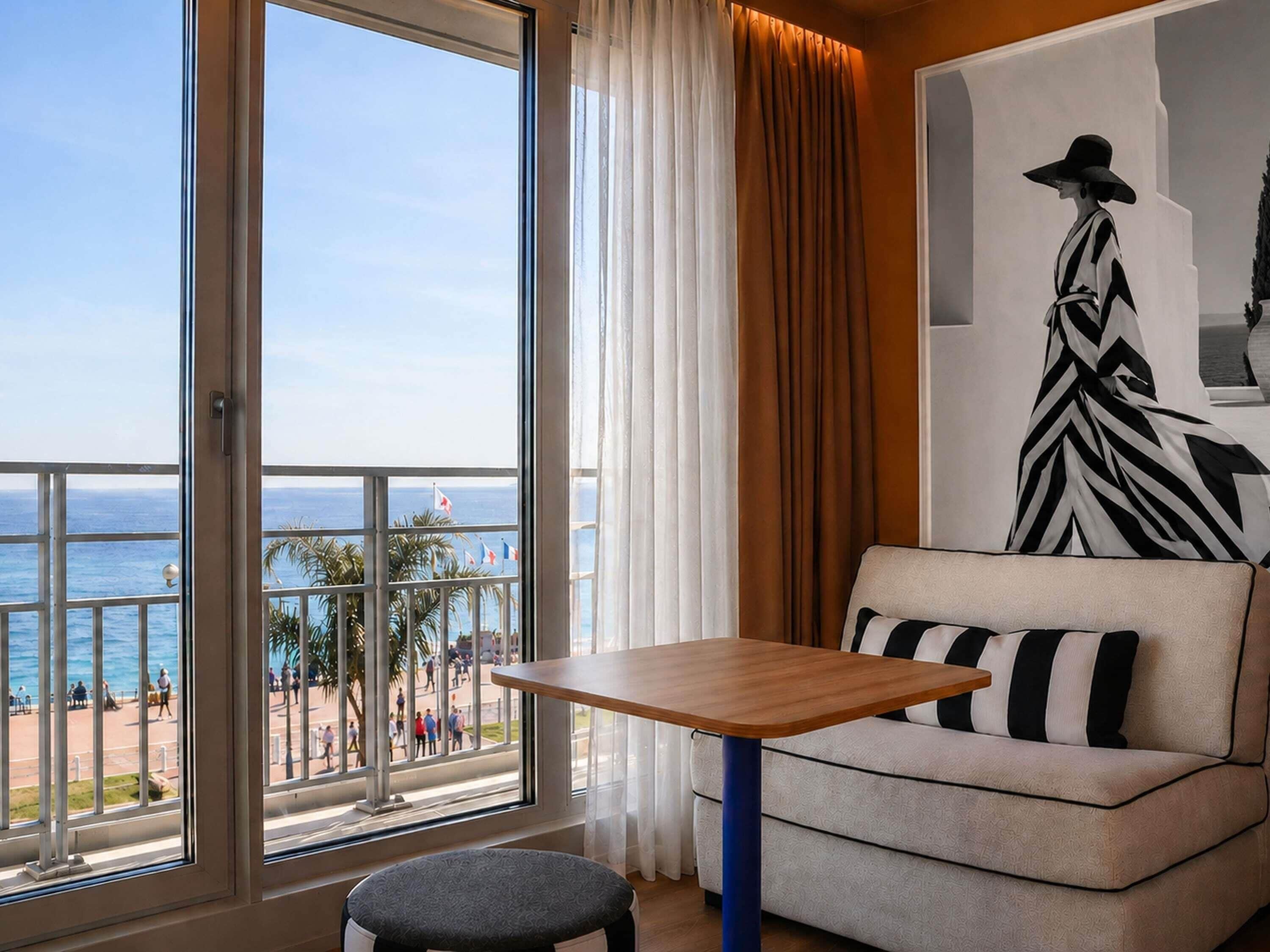 A room with a large window, a sofa, a small table, and a chair.