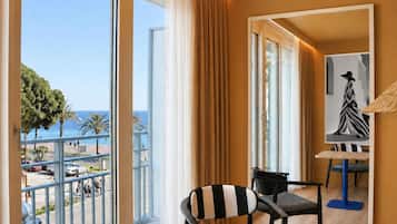 Habitación de hotel con balcón amplio, vista a la playa y un cuadro en la pared.