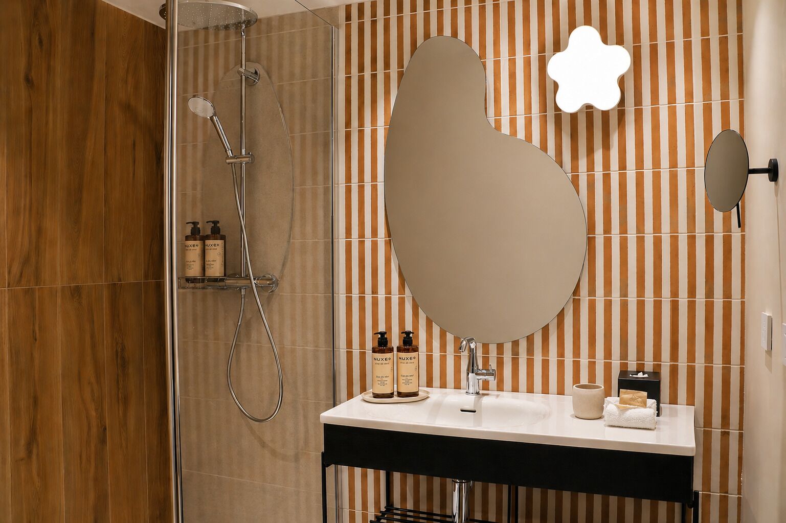 A modern bathroom with a shower, a vanity with a mirror, and striped wall tiles.