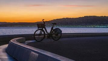 A bicycle parked by a waterfront with a sunset in the background.