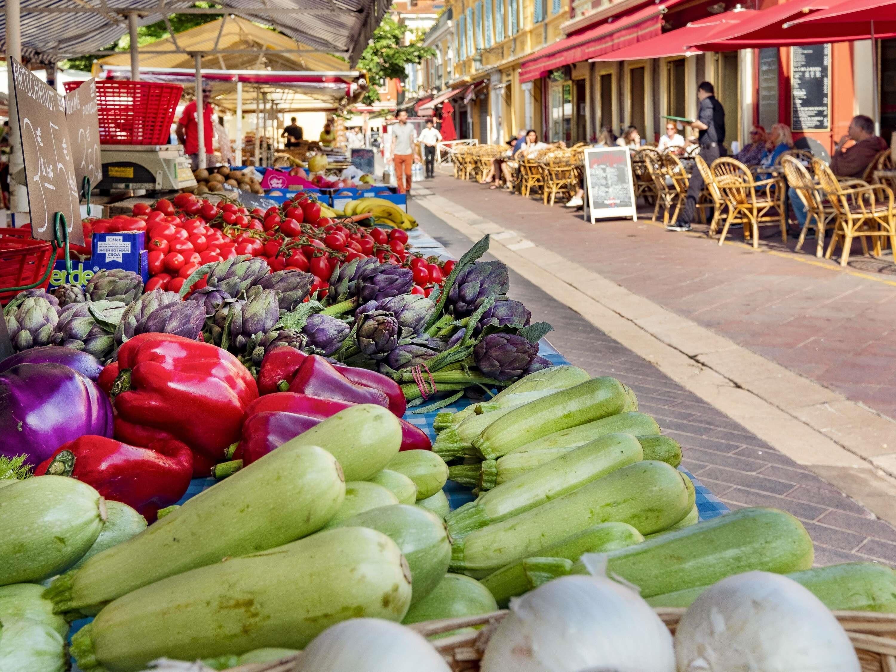Mercado callejero con productos frescos y mesas al aire libre.