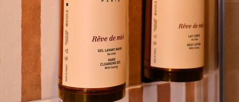 Two Nuxe Paris hand cleansing gel bottles on a tiled wall.