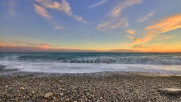 Une plage de galets, avec des vagues et un ciel dégagé.