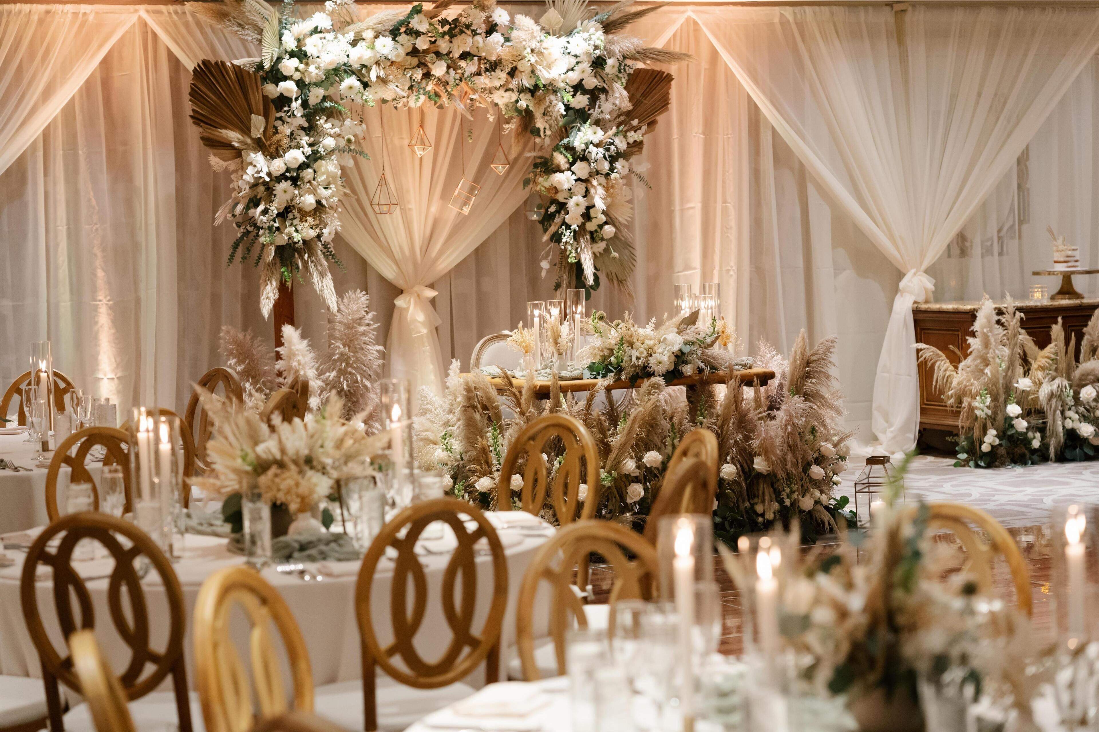 Un salón de banquetes con mesas redondas, sillas y centros de mesa florales.
