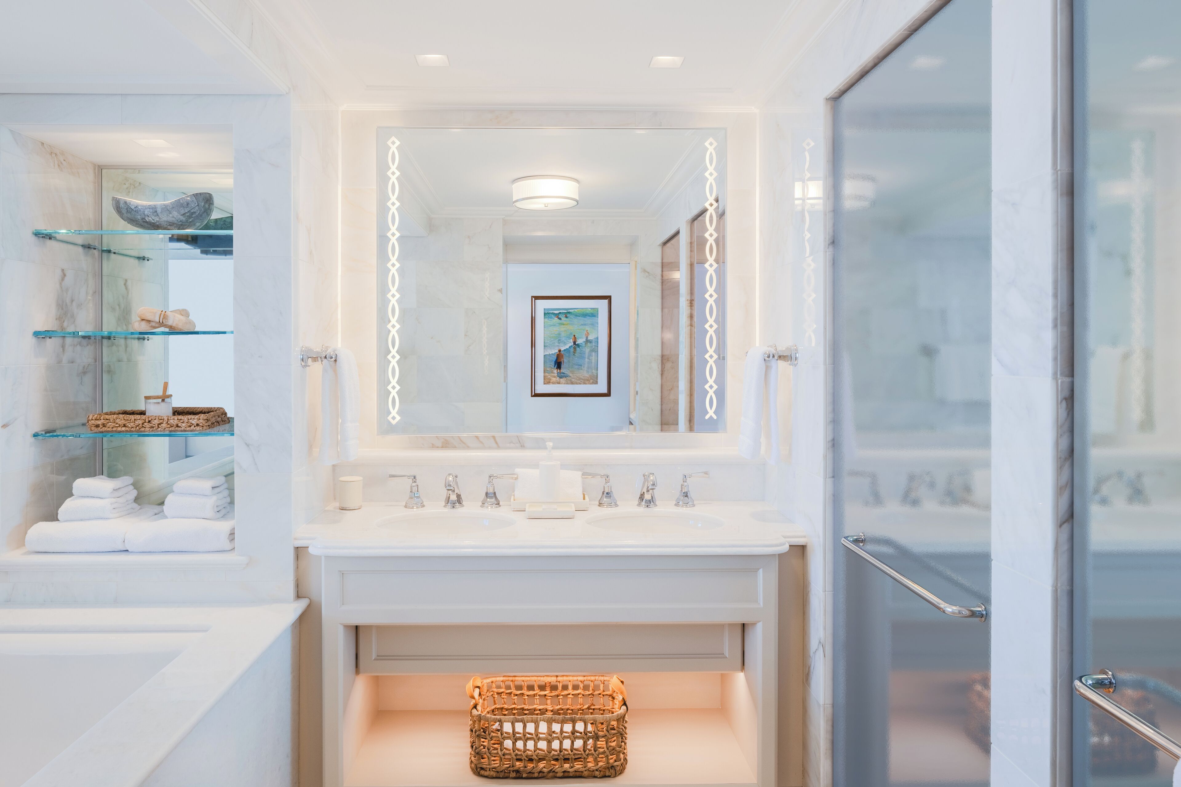 A modern bathroom with a glass shower enclosure, a vanity with a mirror, and a framed artwork above the mirror.