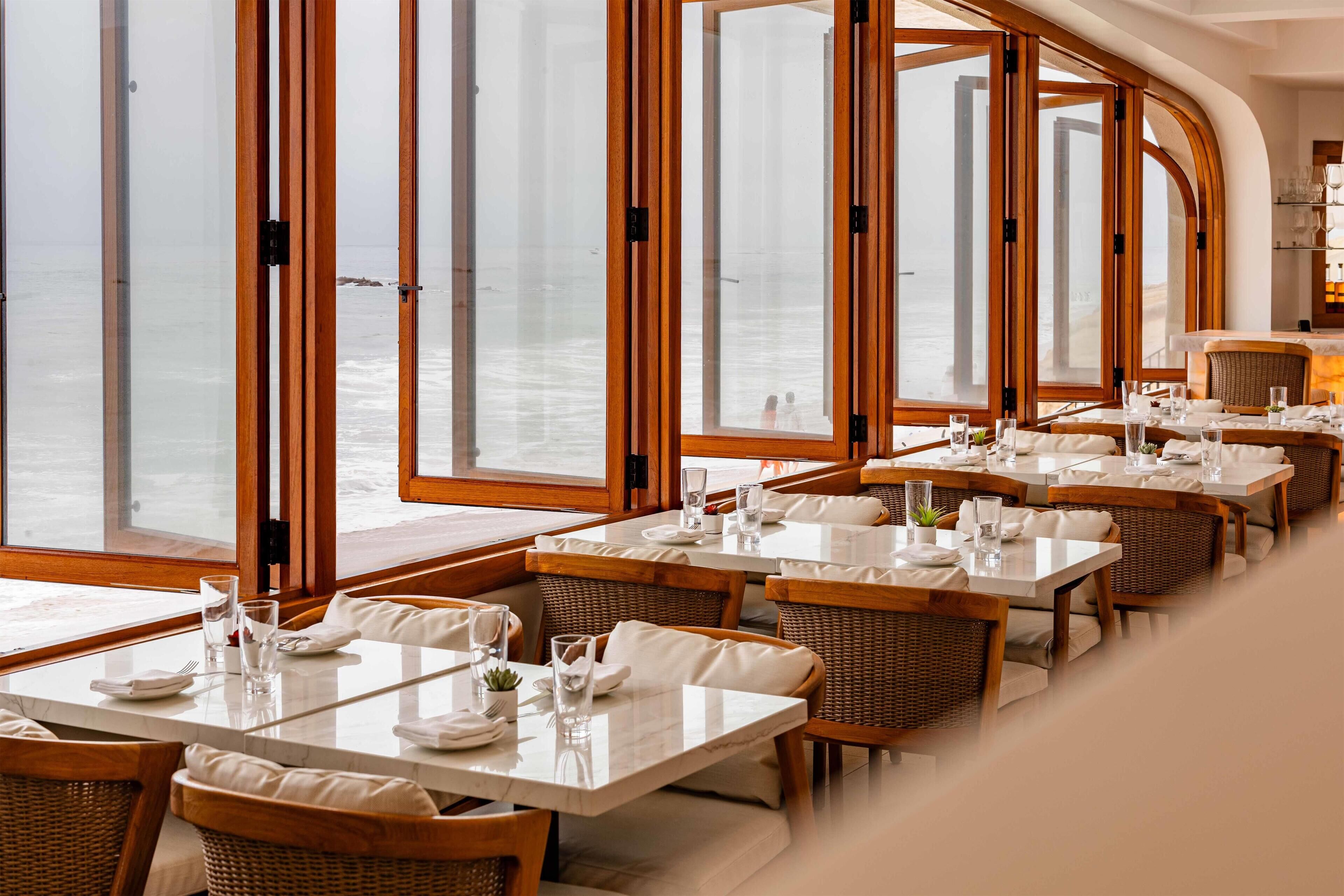 Un ristorante con ampie vetrate, arredi in legno e tavoli disposti con cura.