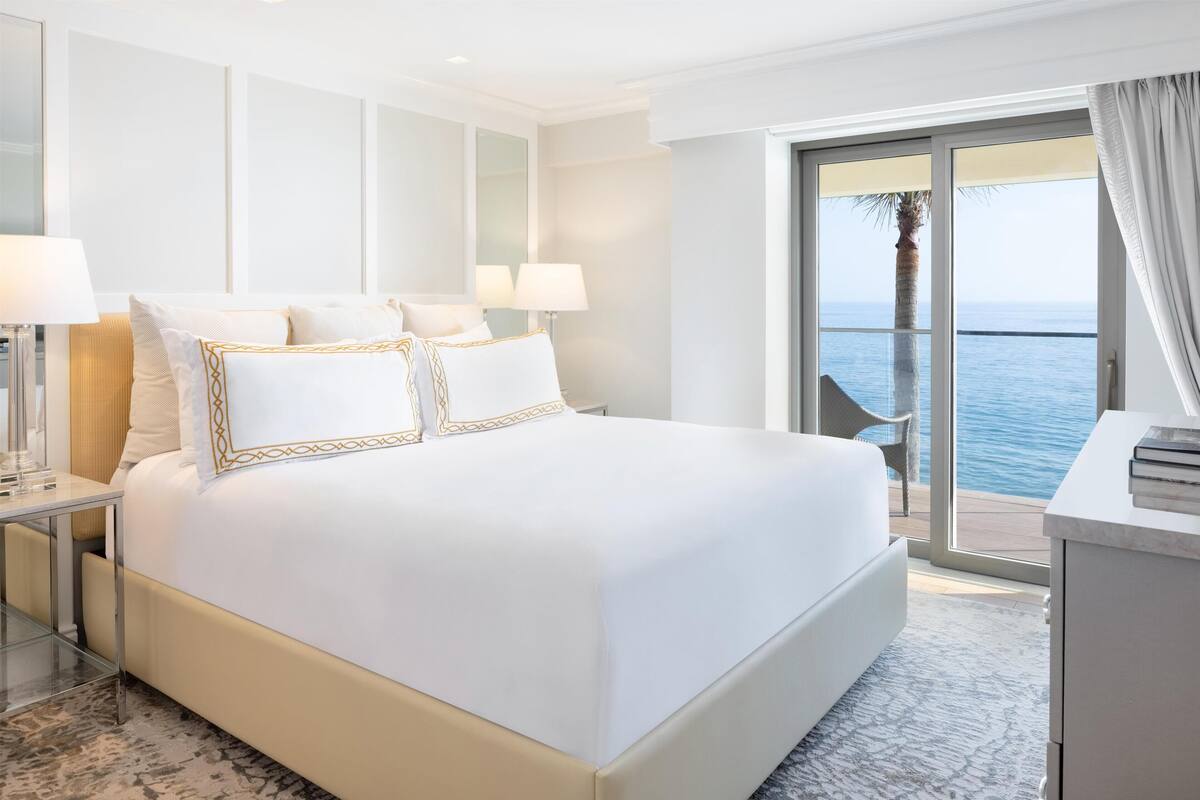 A hotel room with a large bed, a desk, and a view of the ocean.