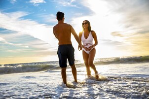 Una pareja de pie en la playa, con olas de fondo.