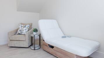 Ein Zimmer mit einer Schlafsofa, einem kleinen Beistelltisch mit Pflanze und einer schlichten weißen Wand.