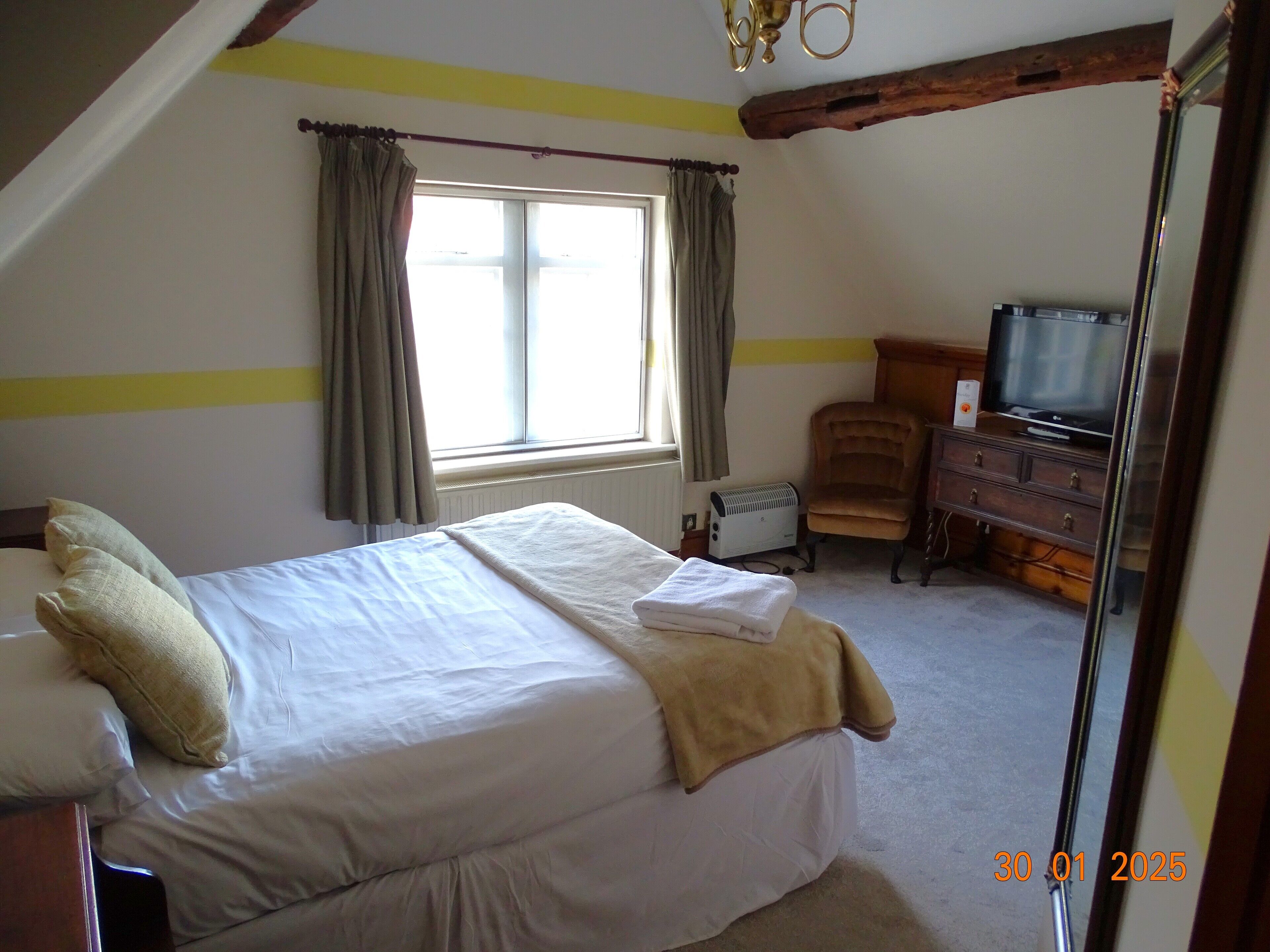A bedroom with a bed, a television, a chair, and a dresser.