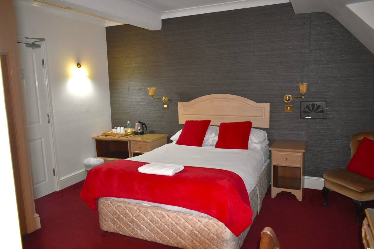 A bedroom with a large bed, two bedside tables, a chair, and a nightstand.