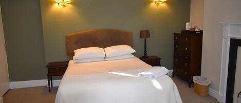 A neatly made bed with white linens, a wooden headboard, and two wall-mounted lamps.