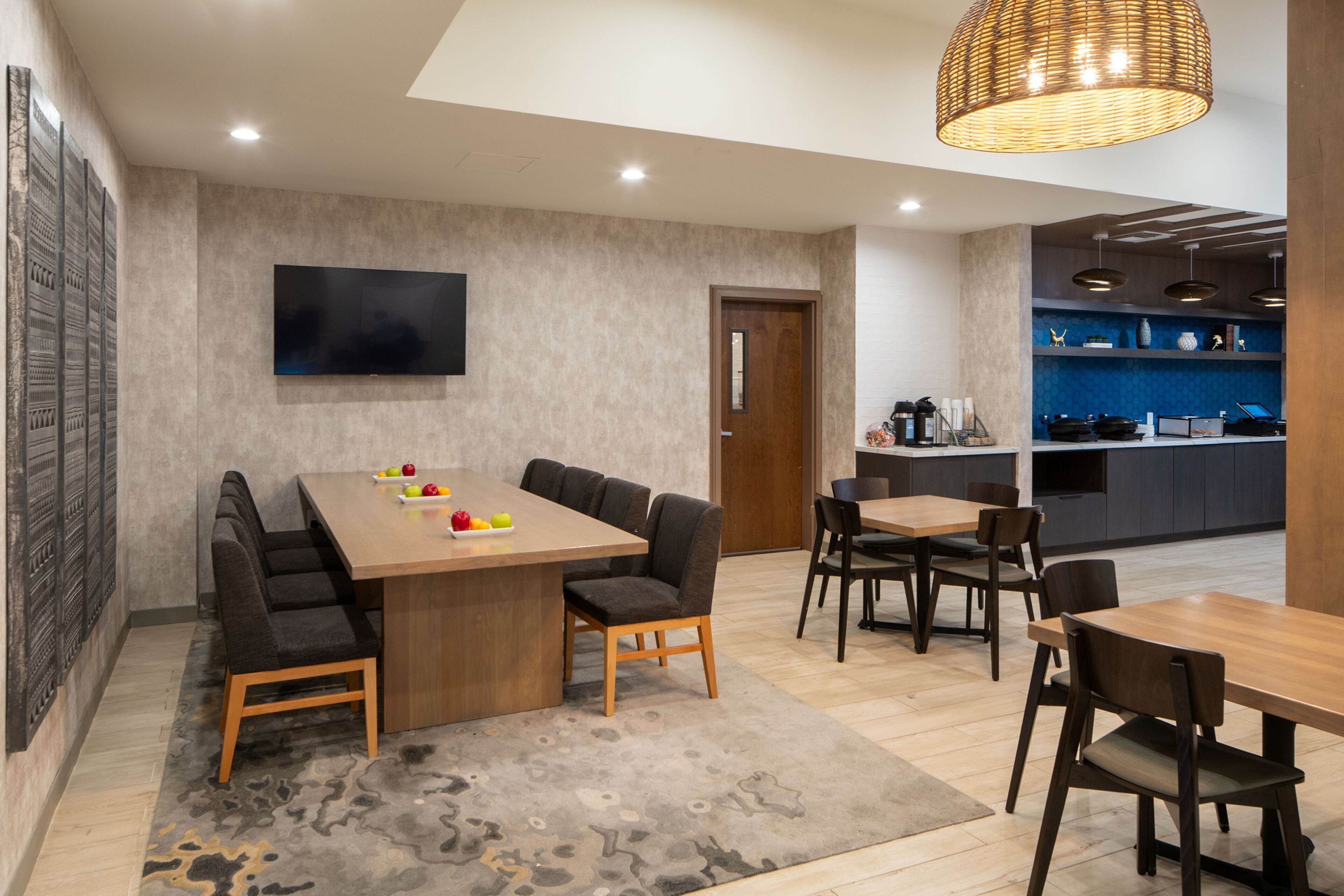Un comedor moderno con una mesa de madera, sillas acolchadas y un televisor de pantalla plana en la pared.