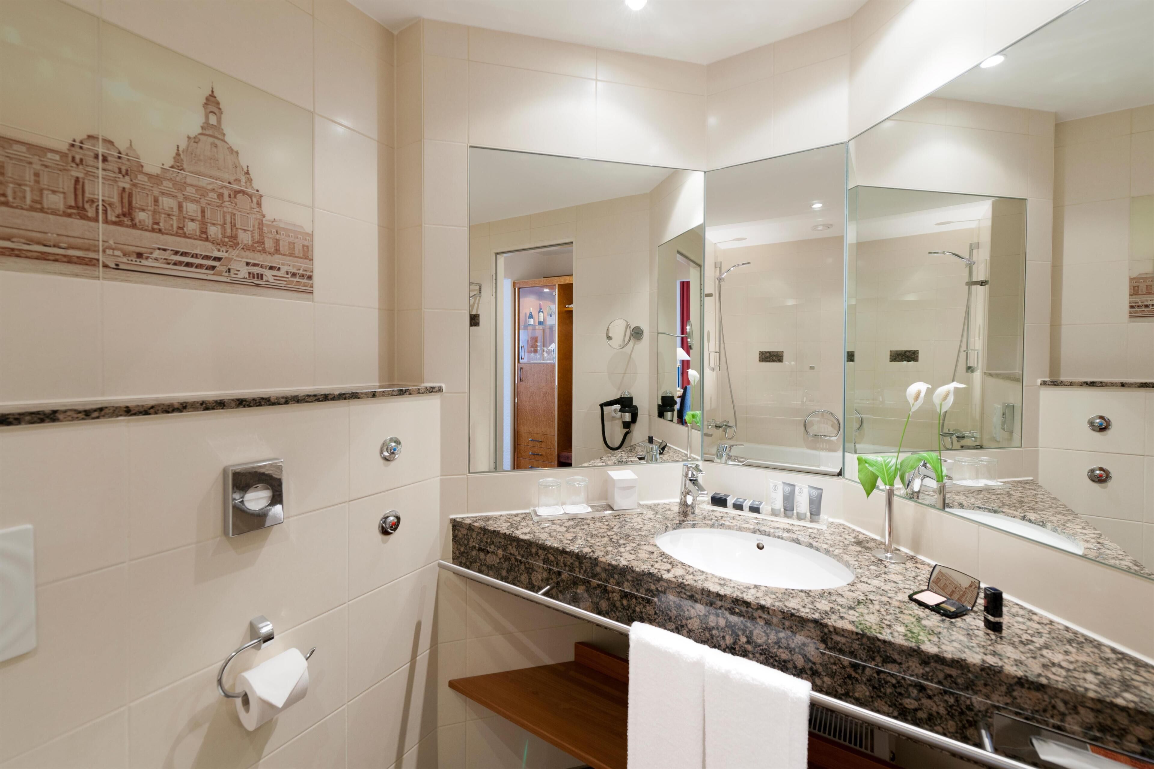 A modern bathroom with a large mirror, a sink, and a toilet.