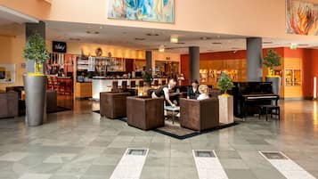 Eine geräumige Lobby mit Sitzbereichen, einer Bar und einem Klavier.