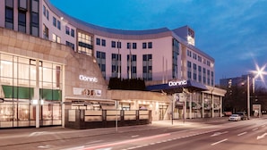 Un hotel Dorint con un diseño arquitectónico moderno, que cuenta con grandes ventanales y una fachada curva.
