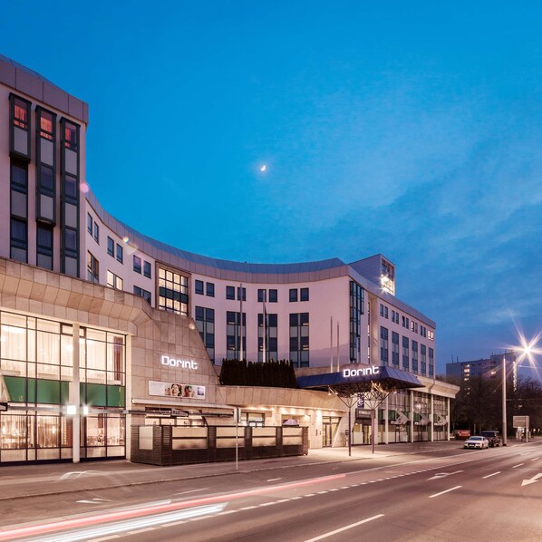Un hotel Dorint con un diseño arquitectónico moderno, que cuenta con grandes ventanales y una fachada curva.