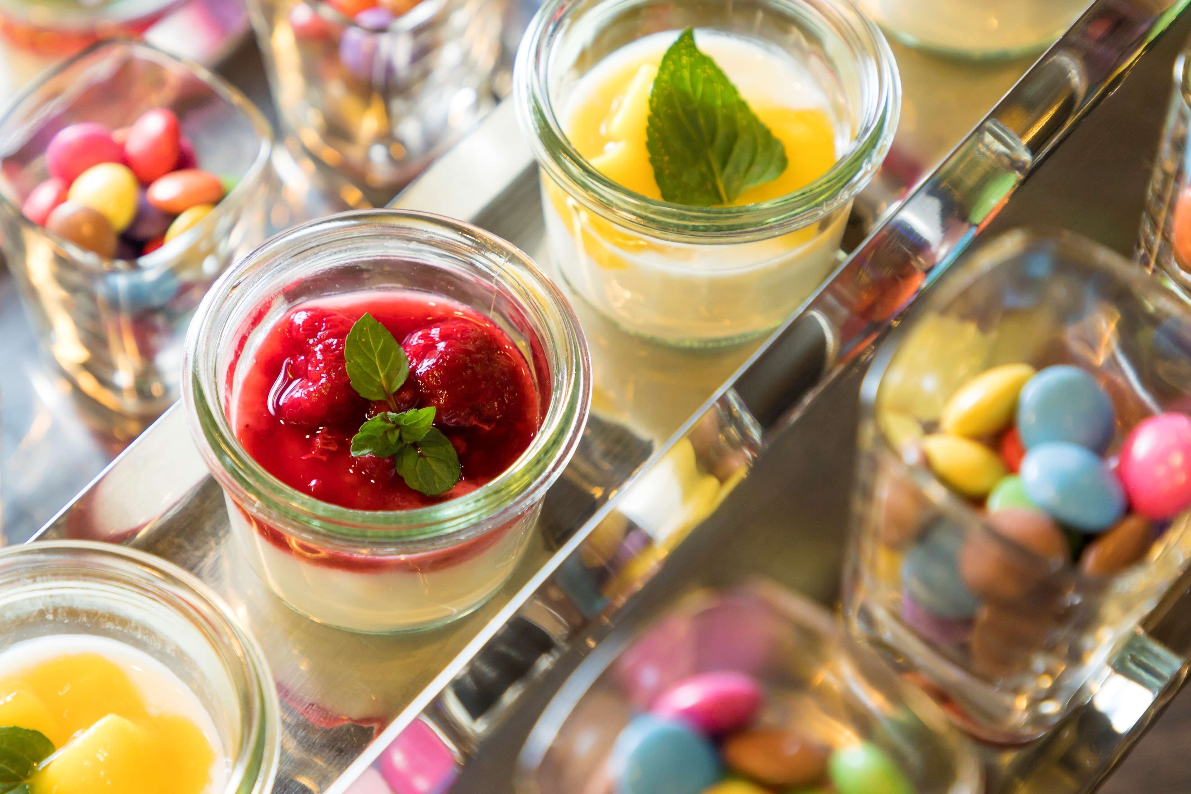 Verschiedene Desserts in Gläsern auf einer Tablett.