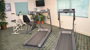 A fitness room with treadmills, a stationary bike, and a wall-mounted TV. - Fairview Inn and Suites (Mobile)