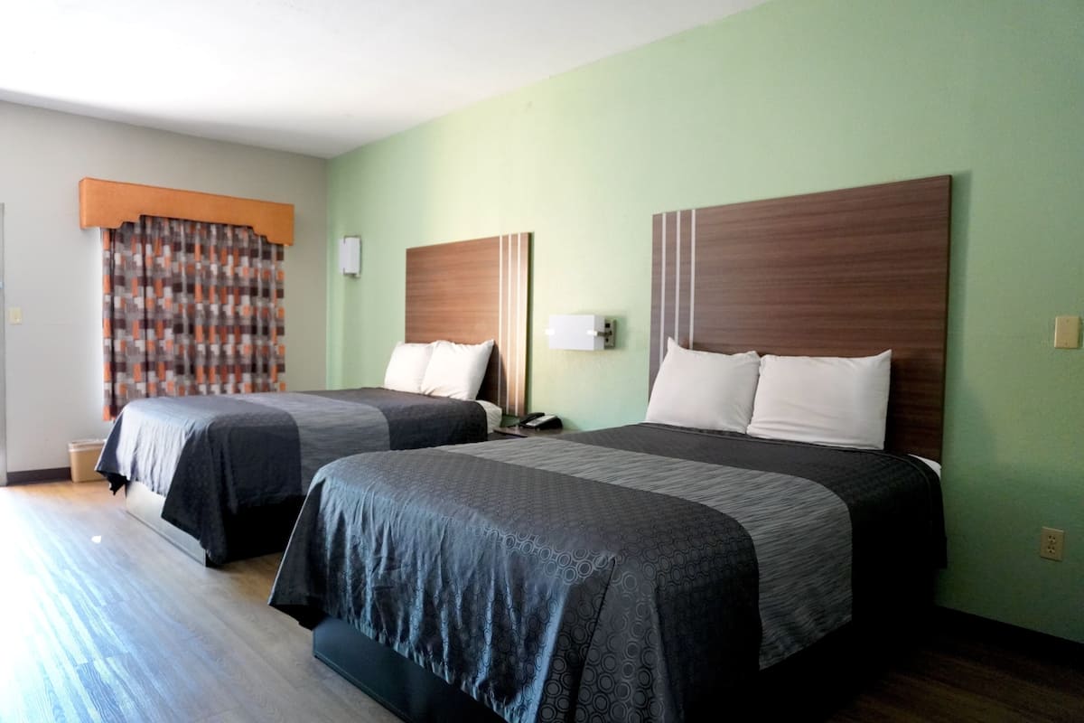Two beds with headboards, a curtain, and a bedside table.