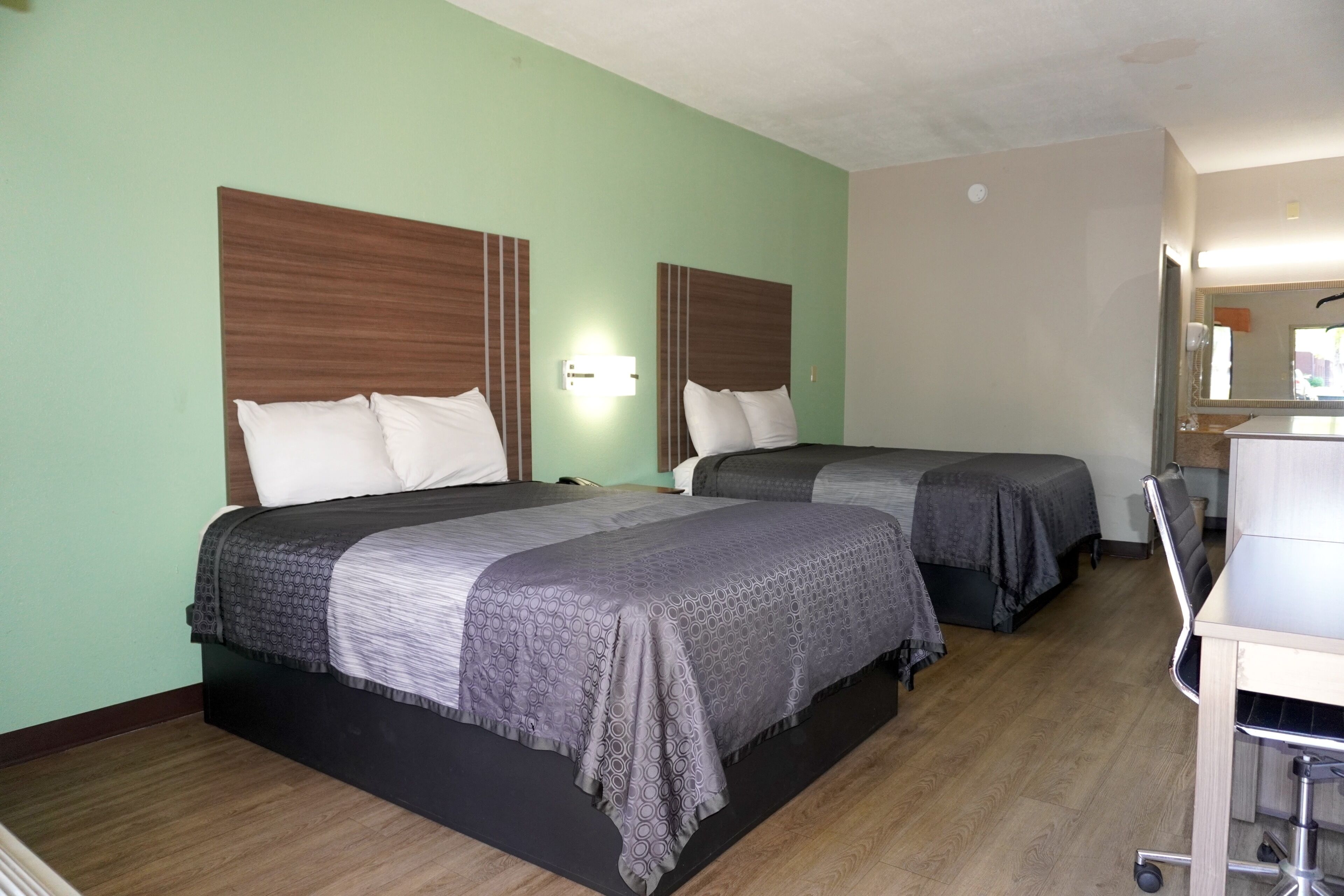 Ein Hotelzimmer mit zwei Betten, einem Schreibtisch und einem Spiegel.
