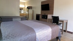 A hotel room with two beds, a desk, a chair, a flat-screen TV, a mirror, and a wardrobe. - Fairview Inn and Suites (Mobile)