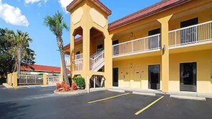 A yellow building with a red roof, a covered outdoor area, and a parking lot. - Fairview Inn and Suites (Mobile)