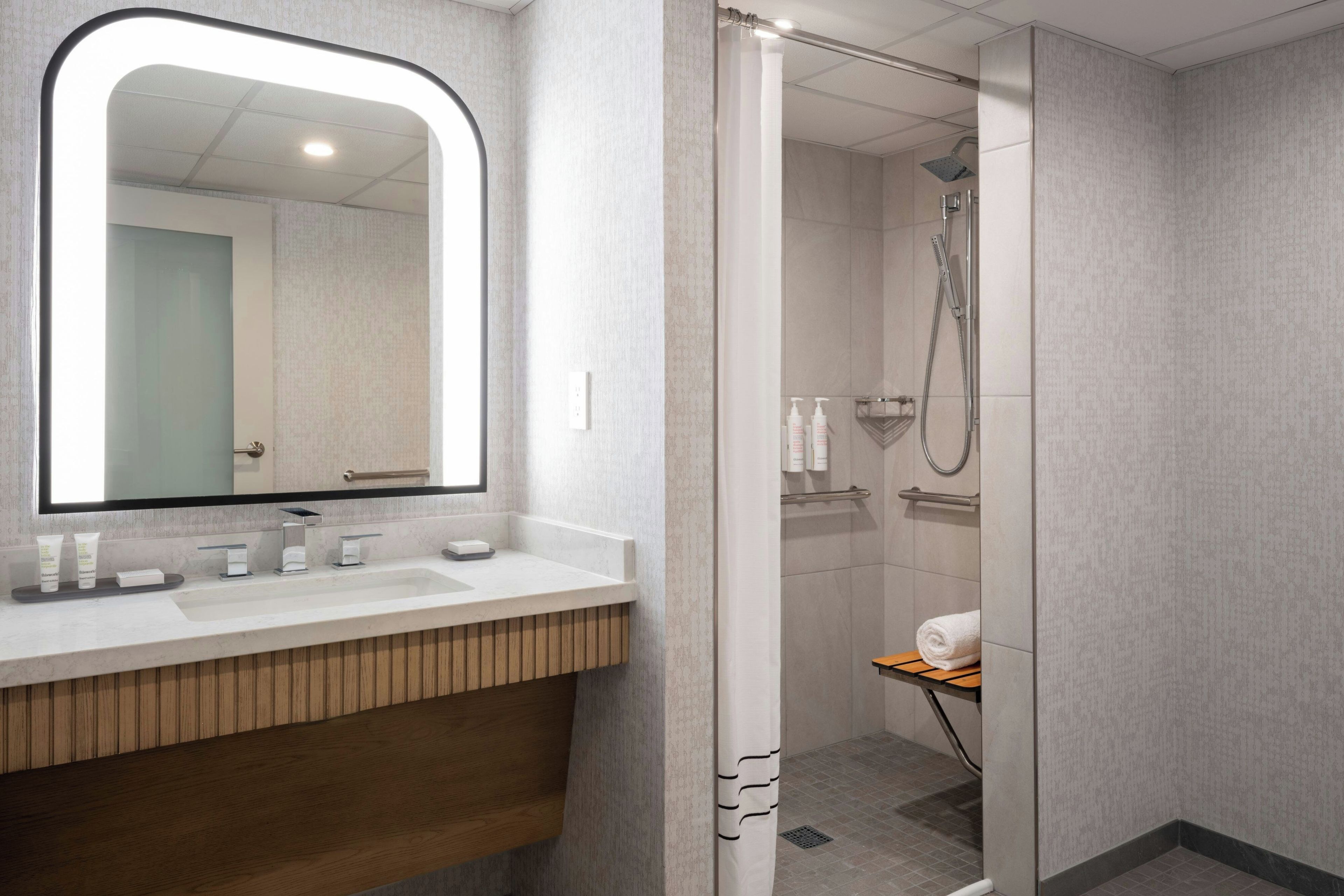 Un baño moderno con un espejo grande, un lavabo y una zona de ducha.