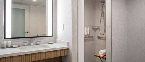 Un baño moderno con un espejo grande, un lavabo y una zona de ducha.