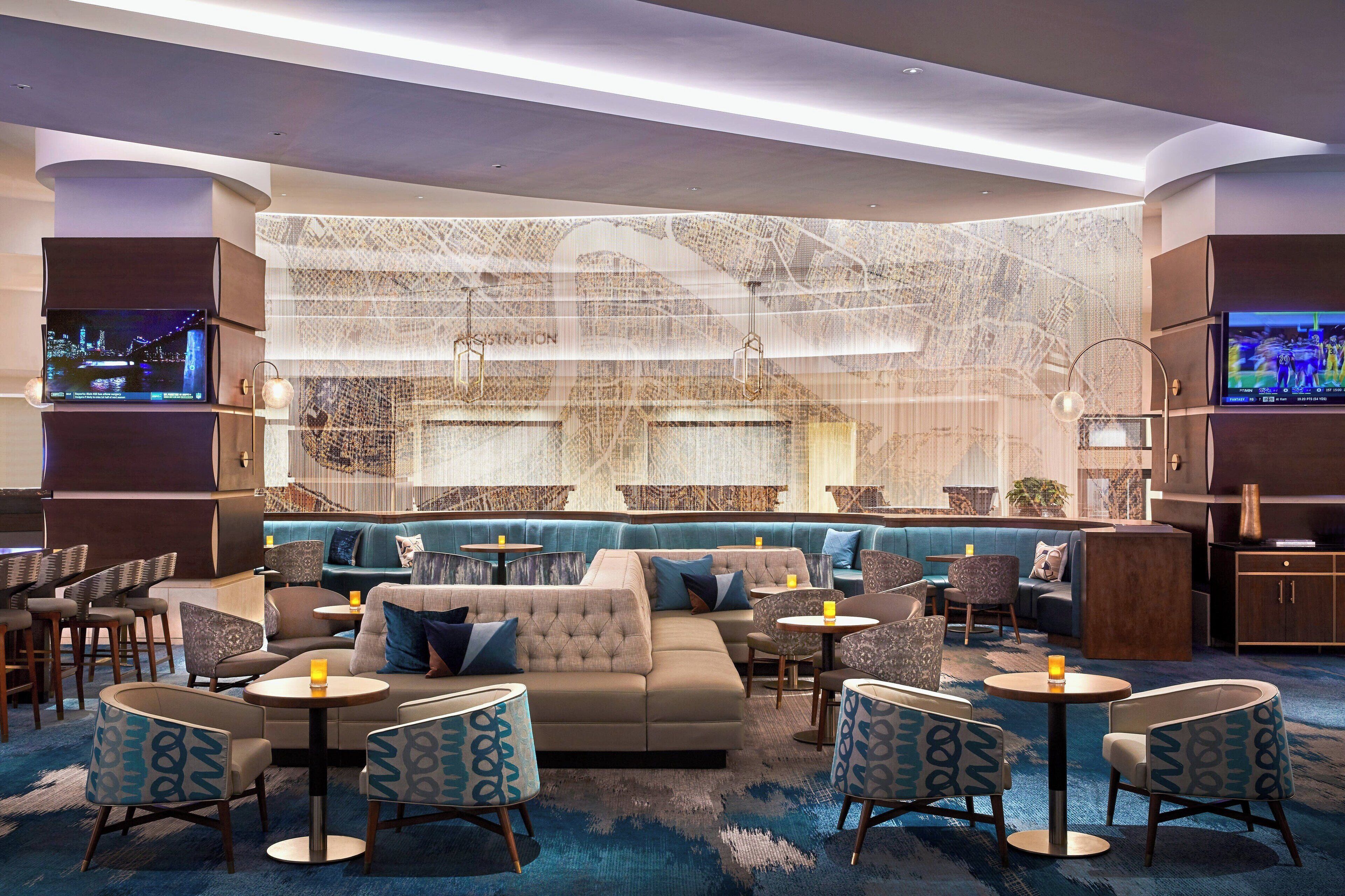 A modern lounge area with sofas, armchairs, and tables, featuring a large wall with a map design.