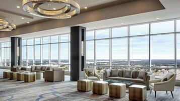 A spacious lobby with large windows, modern furniture, and decorative lighting.