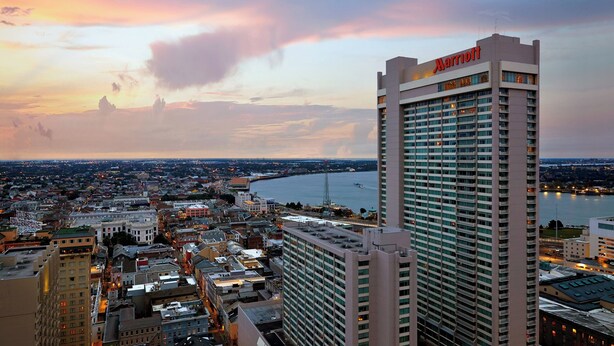 Um hotel Marriott imponente com vista para a paisagem urbana e o rio ao pôr do sol.
