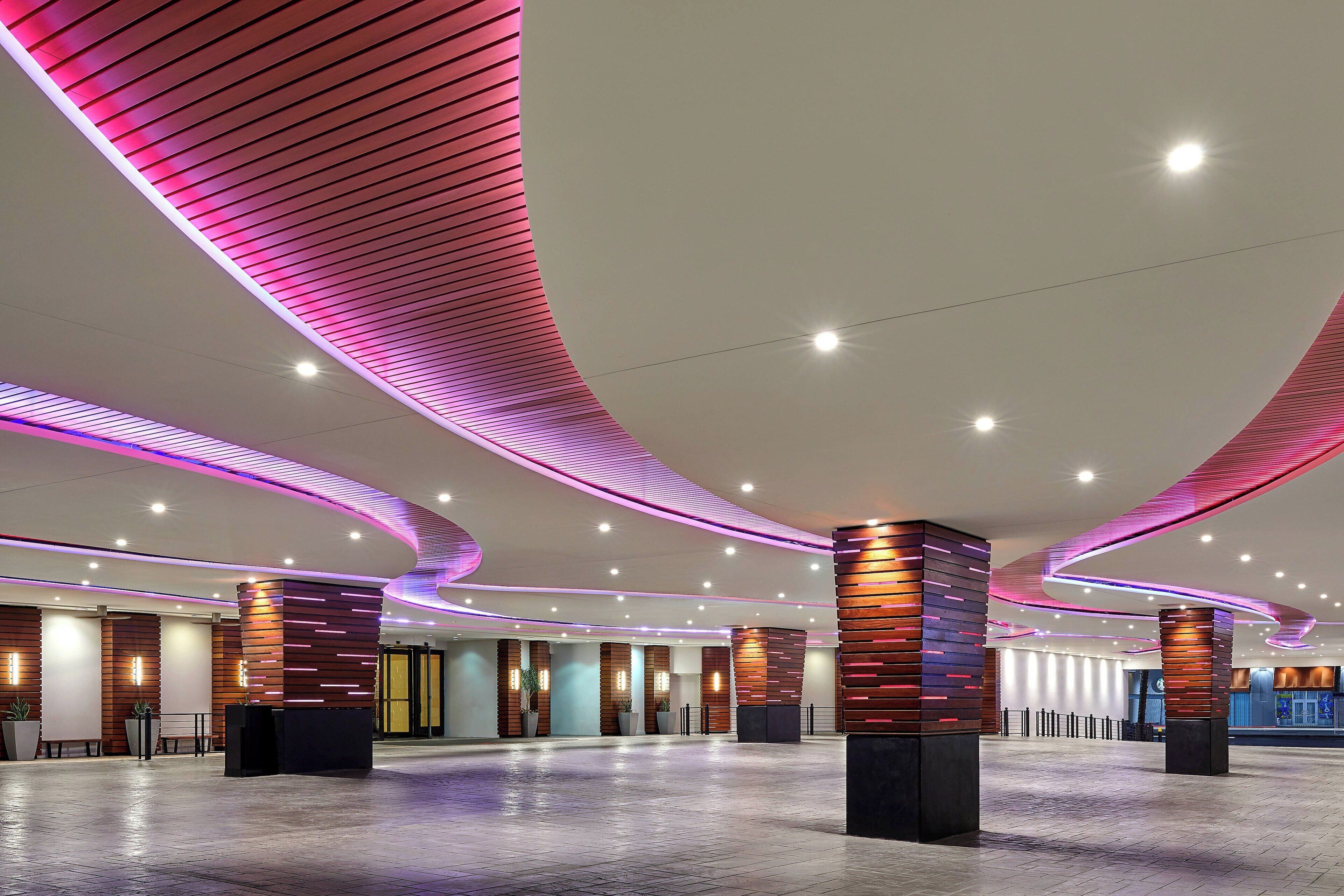 A spacious lobby with curved ceiling lighting, wooden paneling, and a reception desk.