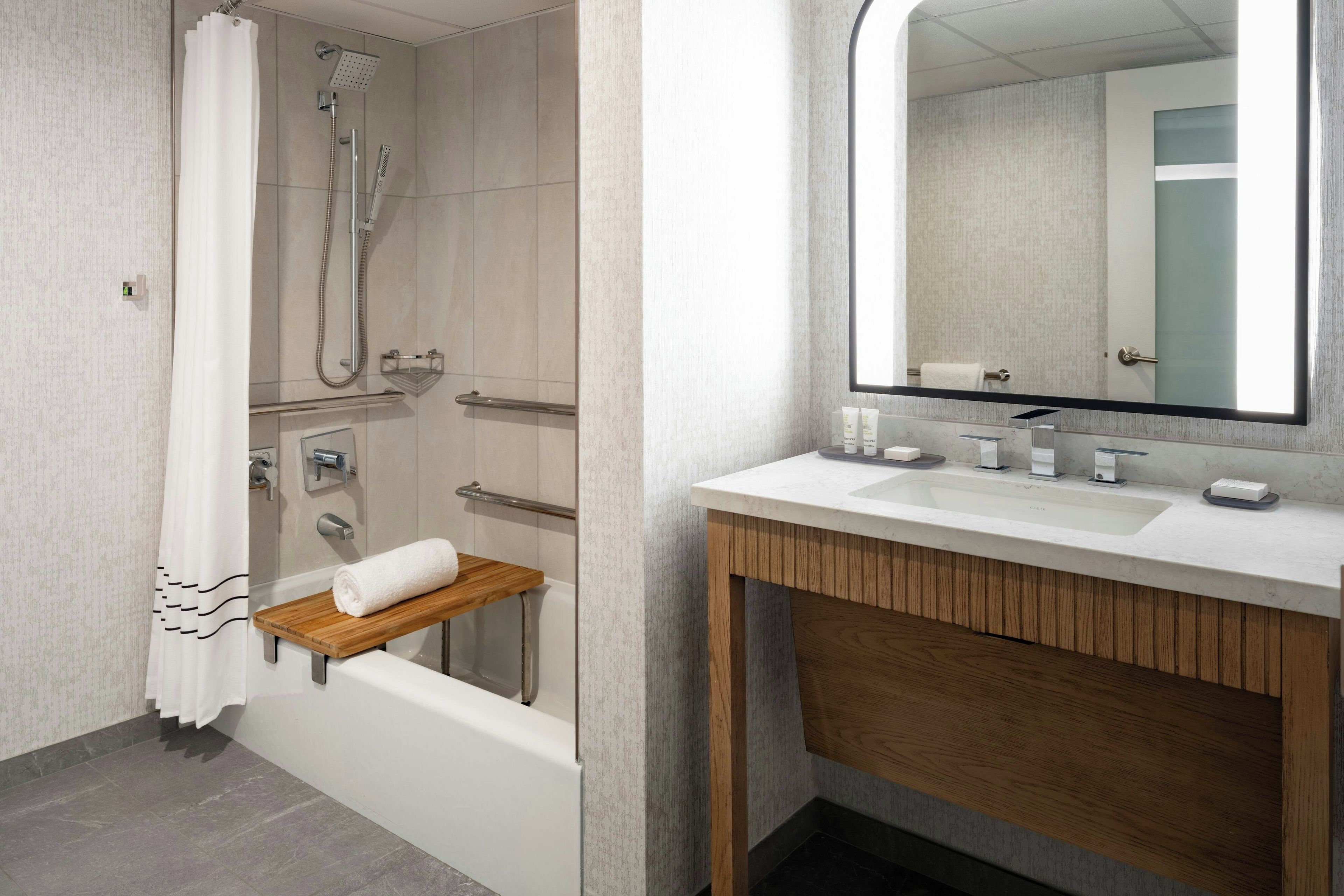 A modern bathroom with a bathtub, shower, vanity with a mirror, and a towel rack.