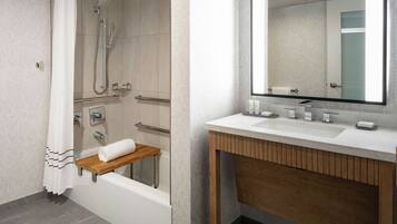 A modern bathroom with a bathtub, shower, vanity with a mirror, and a towel rack.