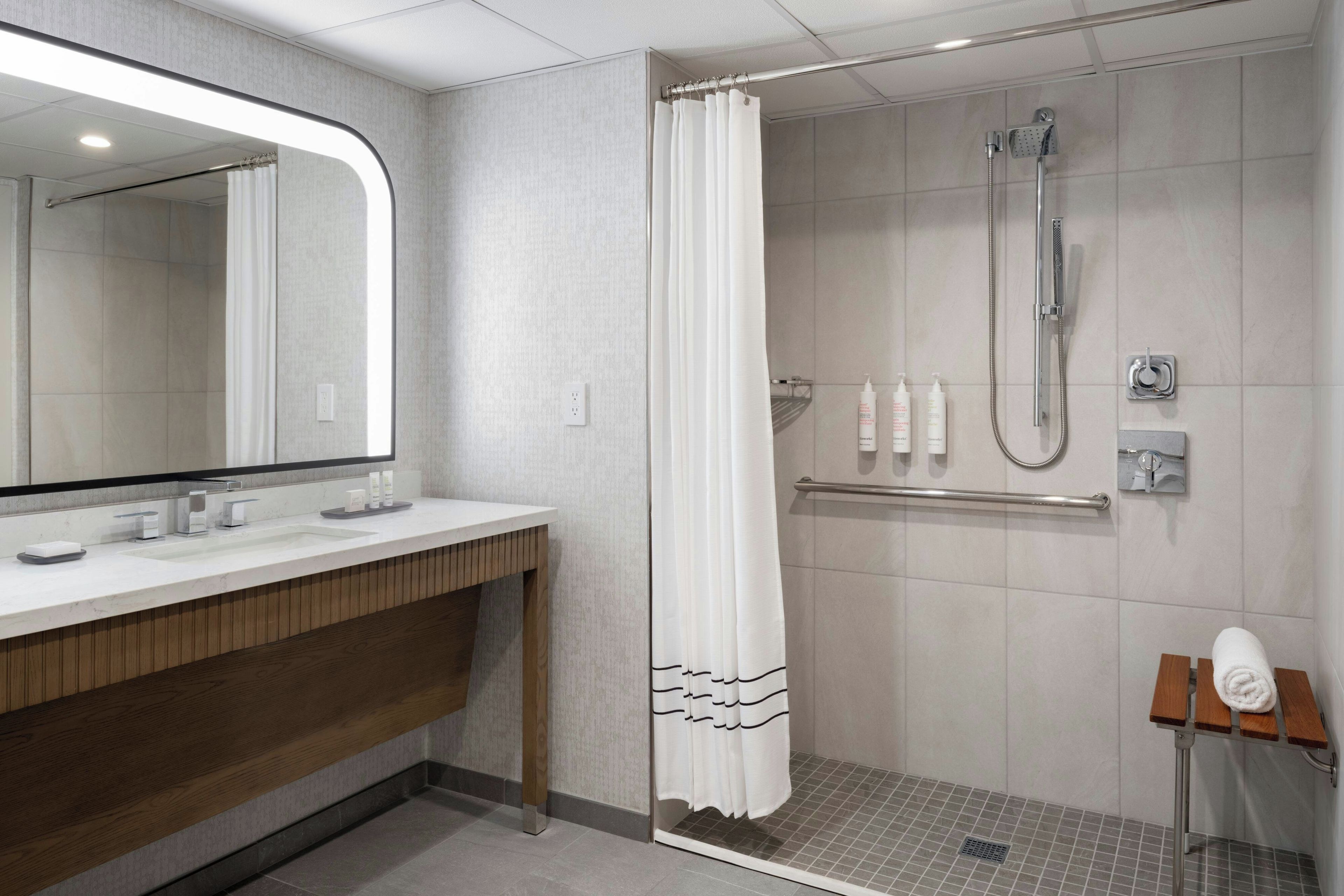 A modern bathroom with a shower, a vanity with a mirror, and a towel rack.
